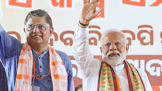 Baijayant Panda and Prime Minister Narendra Modi waving to a crowd in front of an Odia-language backdrop
