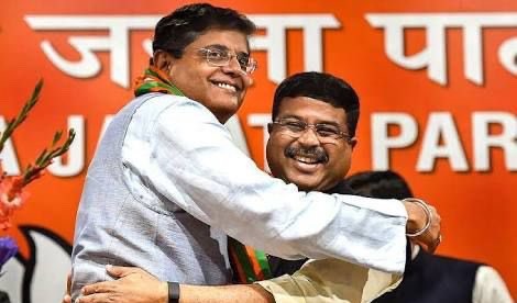 Baijayant Panda embracing Dharmendra Pradhan in front of a Bharatiya Janata Party banner