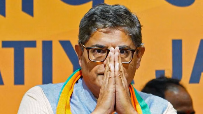 Baijayant Panda with hands folded in greeting, wearing glasses and a saffron and green scarf, in front of a Bharatiya Janata Party backdrop