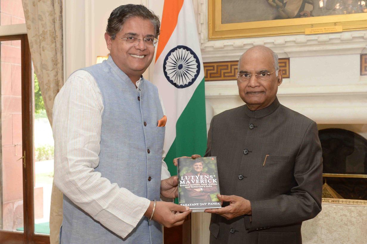 Baijayant Panda, smiling, presents a copy of the book Lutyens’ Maverick to former President Ram Nath Kovind in a formal room with the Indian flag behind them
